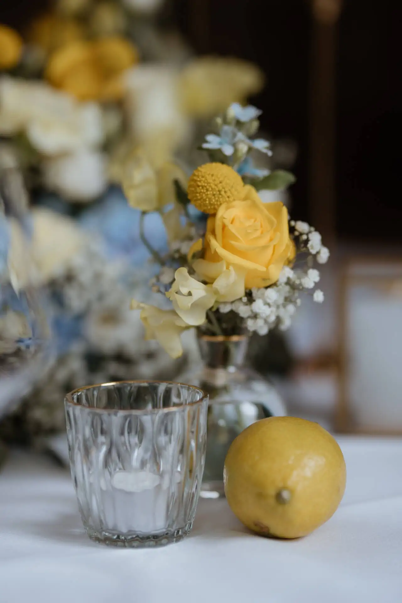 Gelbe Rosen, Kerze und Zitrone auf Tisch