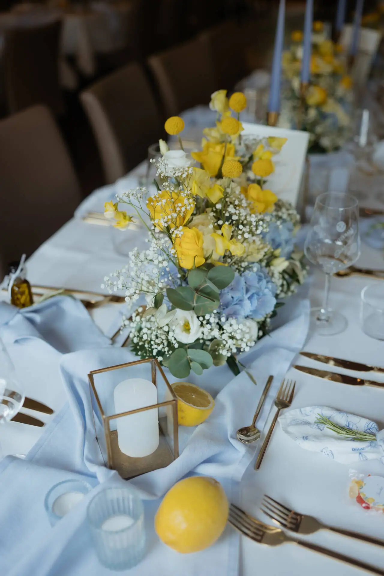 Blumengesteck und Kerze auf gedecktem Tisch.