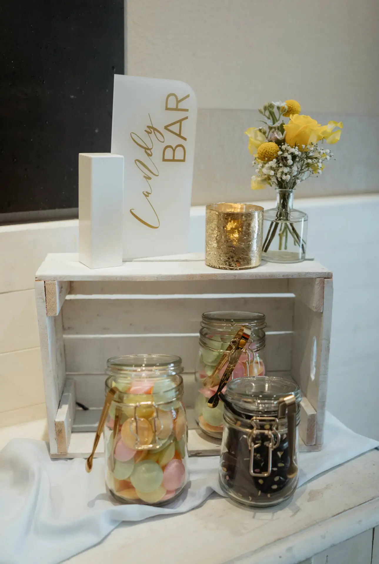 Süßigkeitenbar mit Gläsern und Blumen.