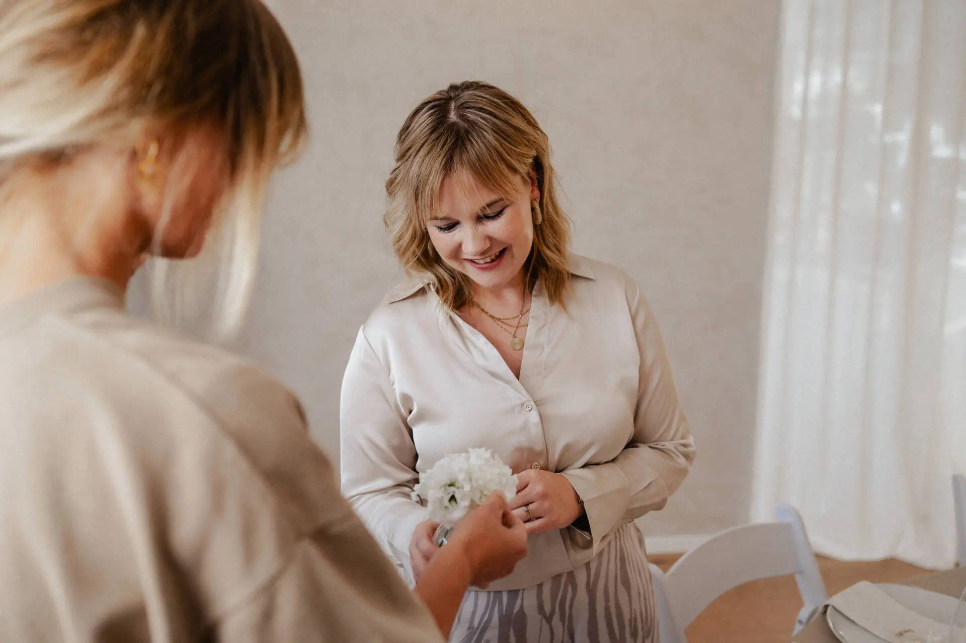 Zwei Frauen, Blumenstrauß überreichen, helle Umgebung.