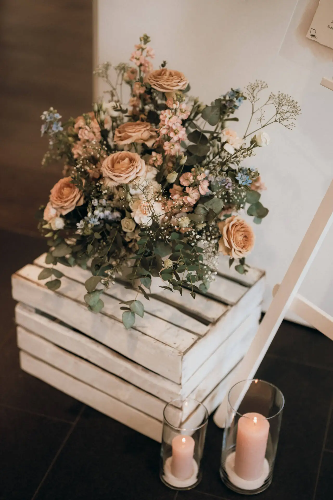 Blumenstrauß auf Holzkiste mit Kerzen daneben