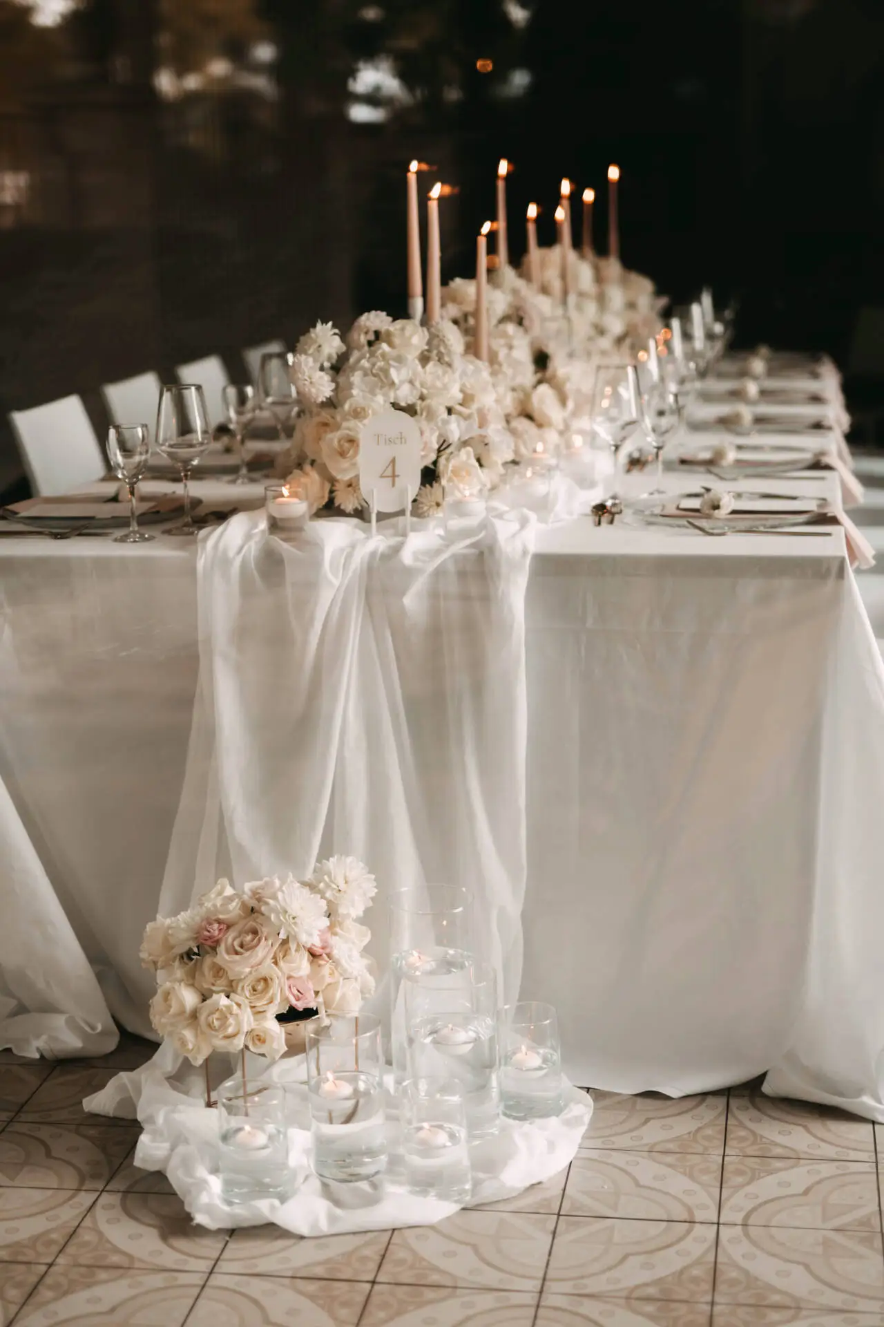 Elegante Hochzeitstafel mit Kerzen und Blumen dekoriert.