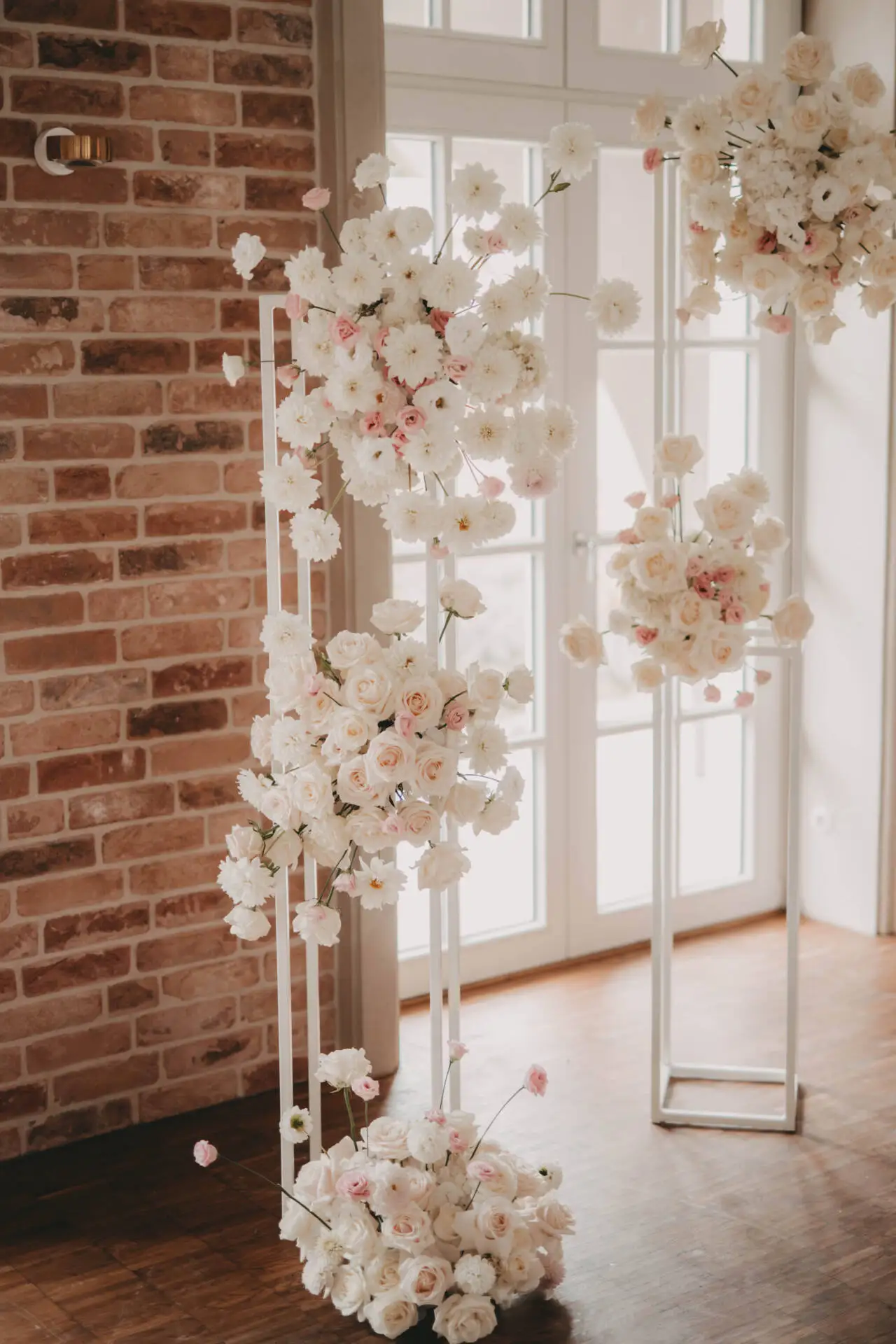 Blumenarrangement neben Fenster auf Holzfußboden.