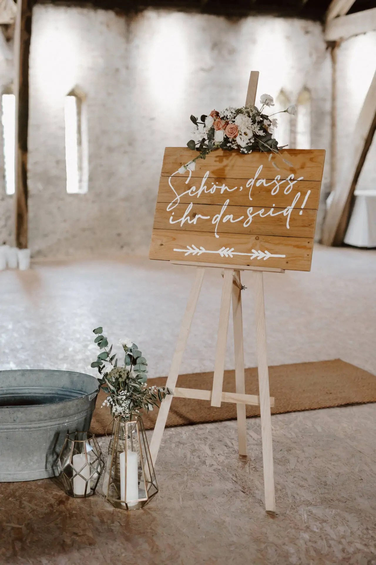 Willkommensschild mit Blumen auf Staffelei