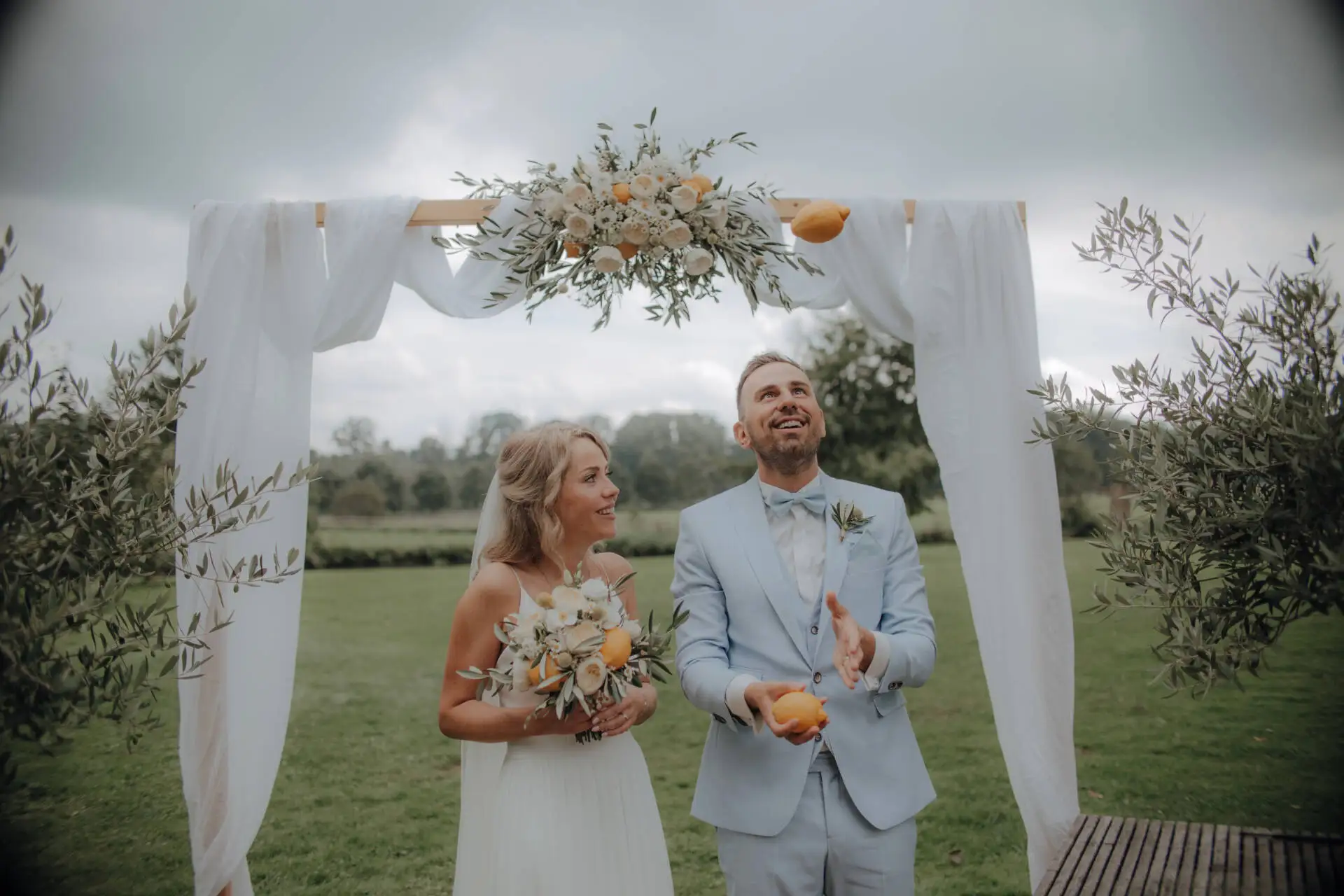 Brautpaar lächelt unter Blumenbogen im Freien