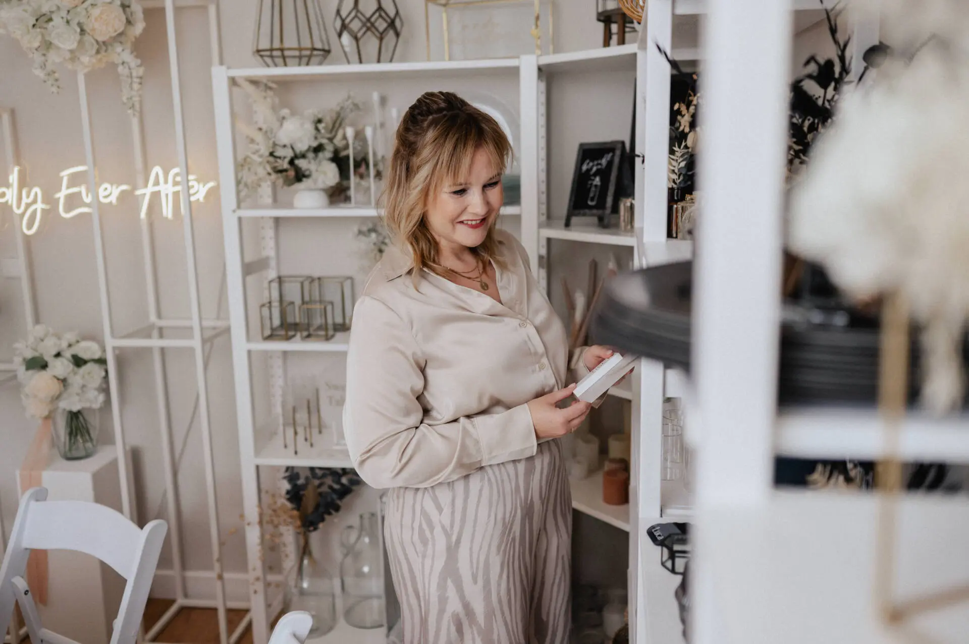 Frau in einem dekorierten Raum lächelt und liest.