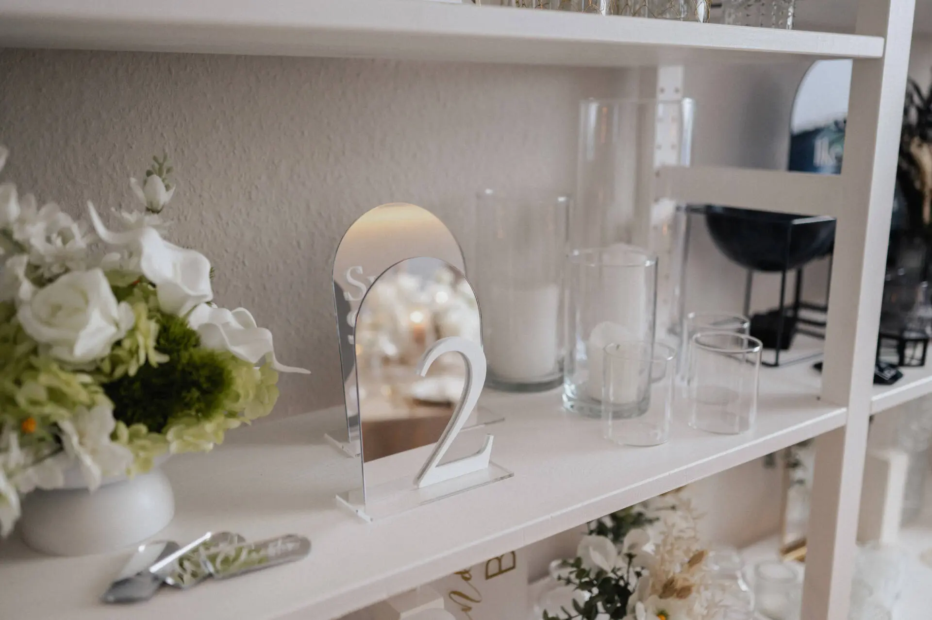 Dekoration auf einem Regal mit Blumen und Kerzen.